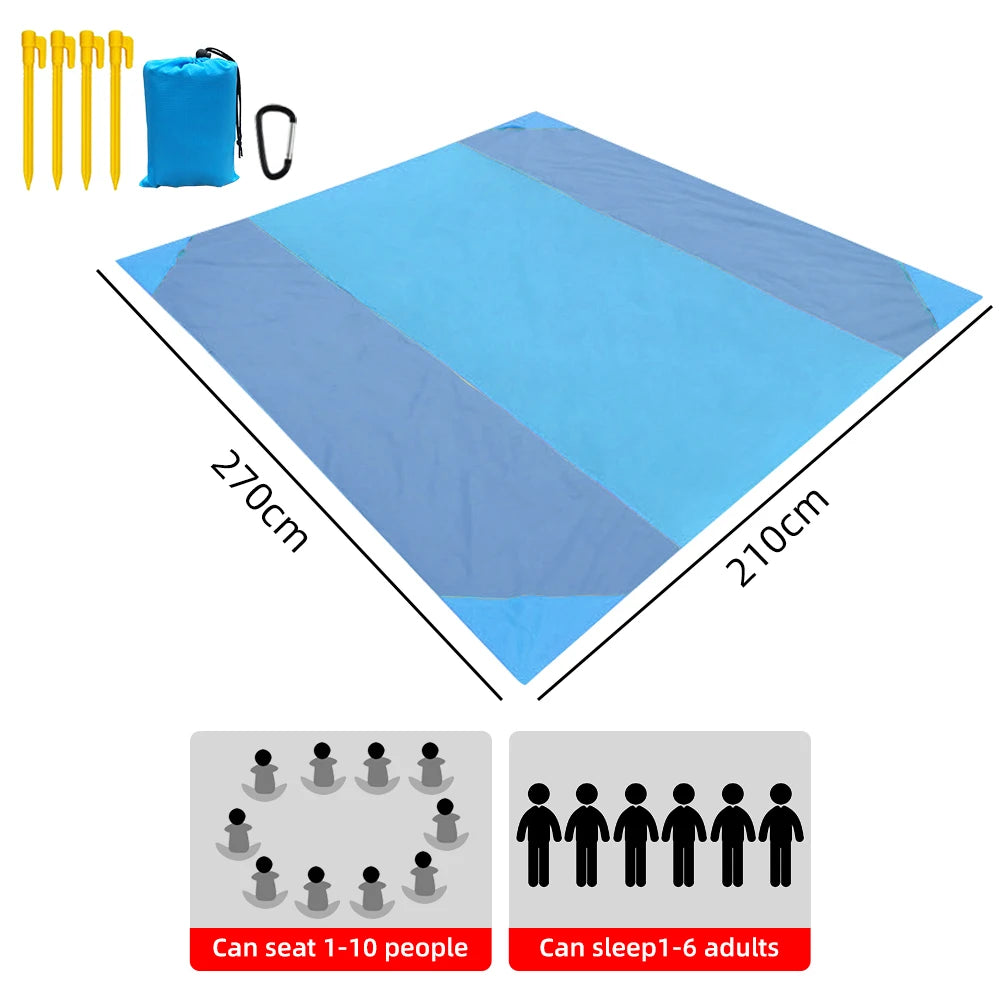 A sturdy, light and portable waterproof outdoor mat spread out on a sandy beach. The mat is designed with durable water-resistant polyester on top and fortified waterproof PVC at the bottom to ensure longevity. Four pegs at the corners of the mat provide stability. The image shows the mat in folded state held together by a stylish silver buckle and stored in a convenient carry bag. Suitable for camping, picnics and beach outings. 